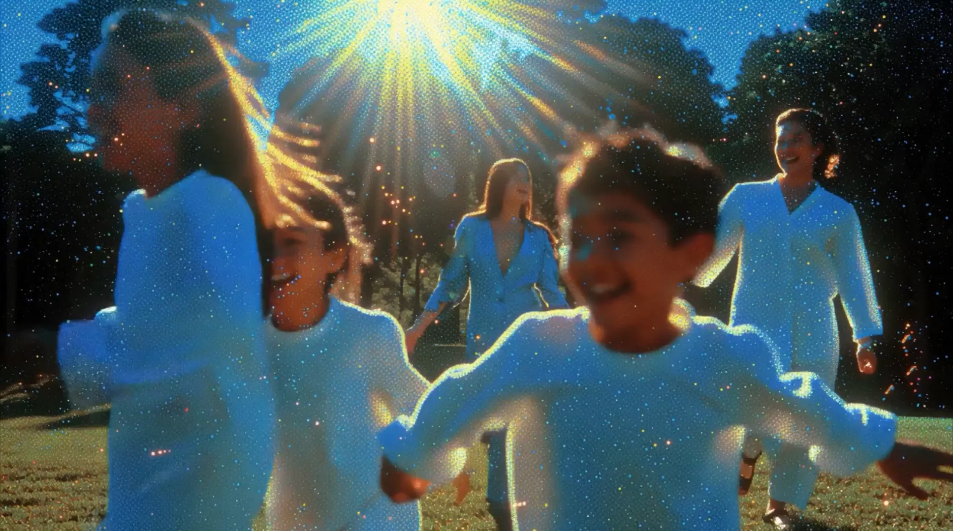 Group of smiling children and a woman walking outdoors in sunlight with sparkles overlay.