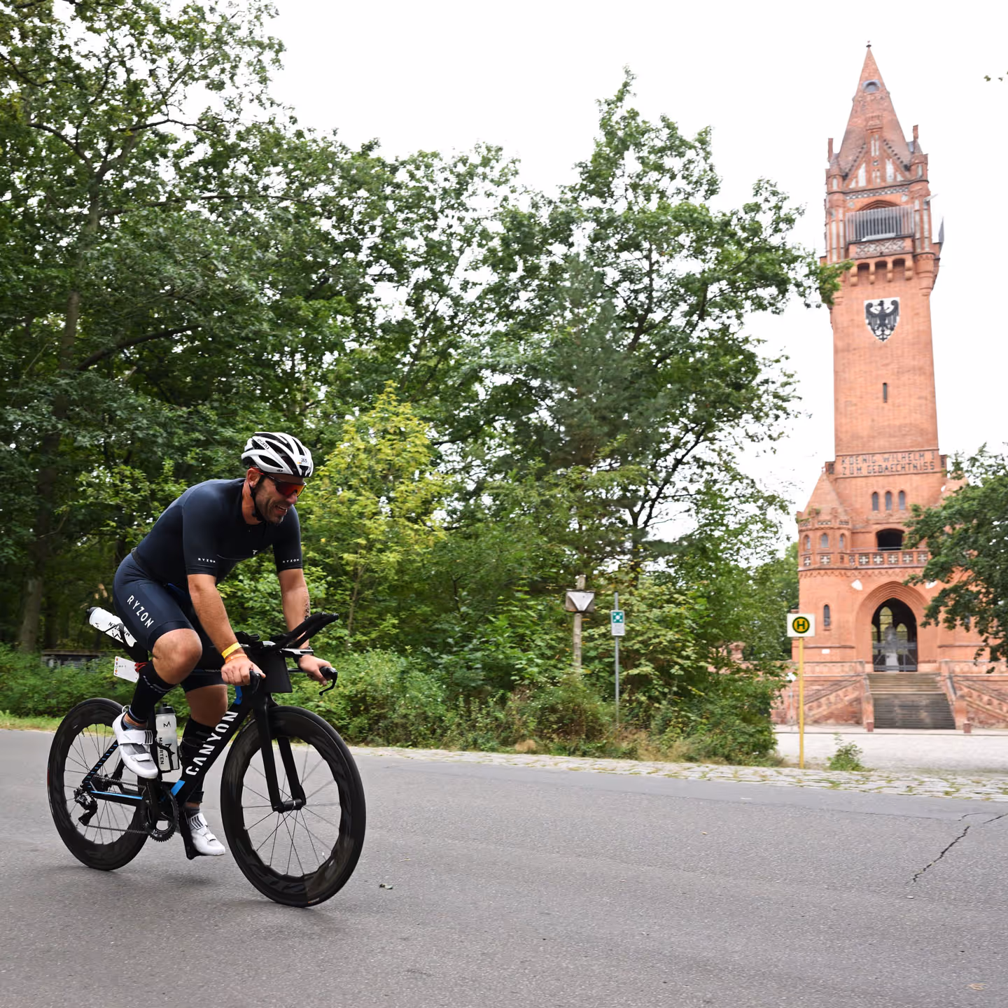 Triathlet auf Zeitfahrrad fährt am Grunewaldturm vorbei auf der Radstrecke