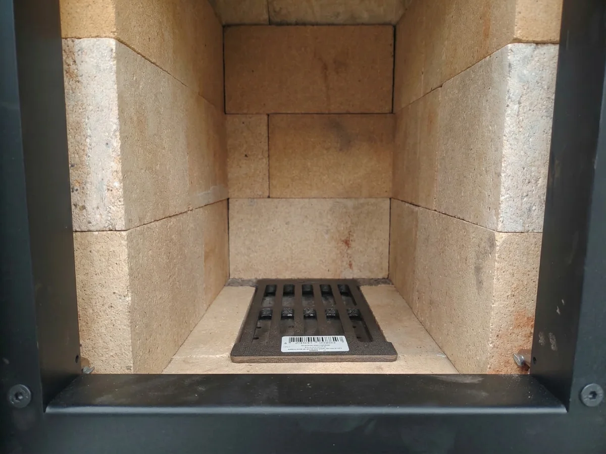 Lähikuva Hehku-takan tulipesästä. Kuvassa näkyy kestävä varaava tiilisydän, siisti ladonta ja valurautainen arina.