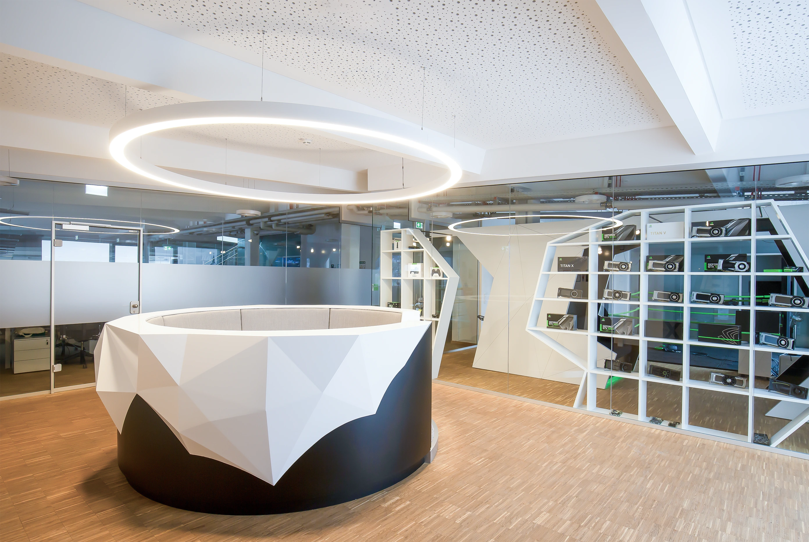 A futuristic reception desk under a large circular light fixture in a modern office atrium.