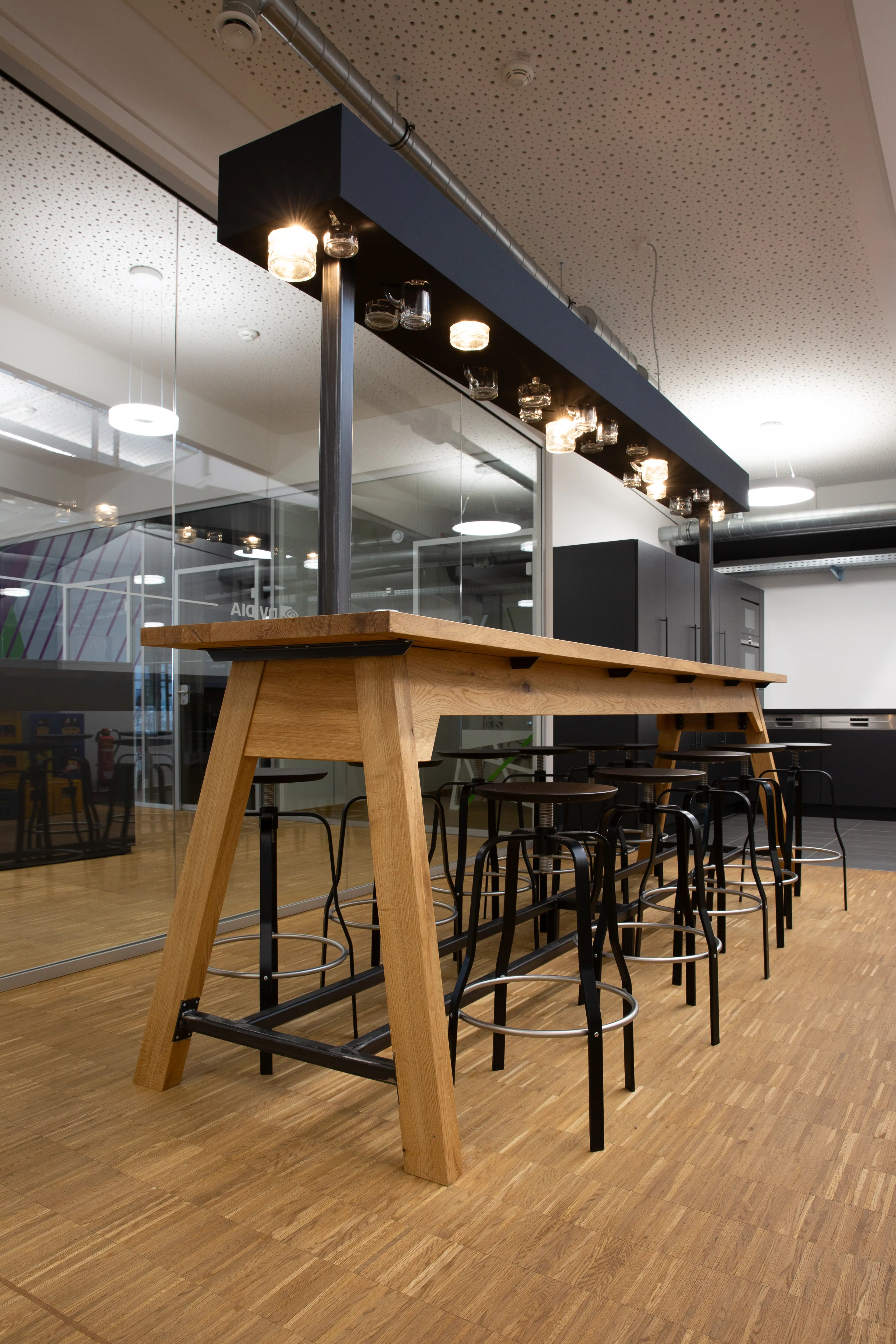 An industrial-style cafeteria with high tables, metal stools, and exposed ceiling fixtures.