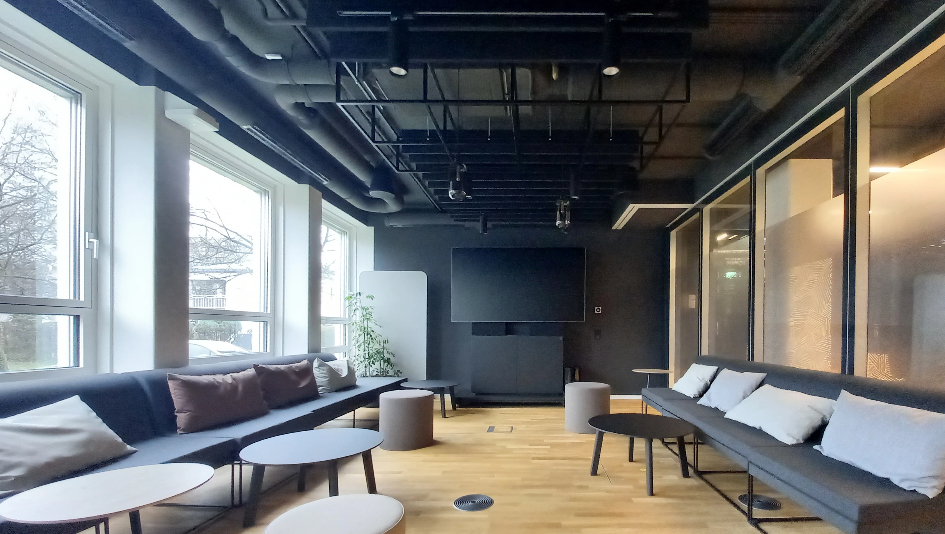 A contemporary lounge area with dark walls, large windows, and comfortable seating.
