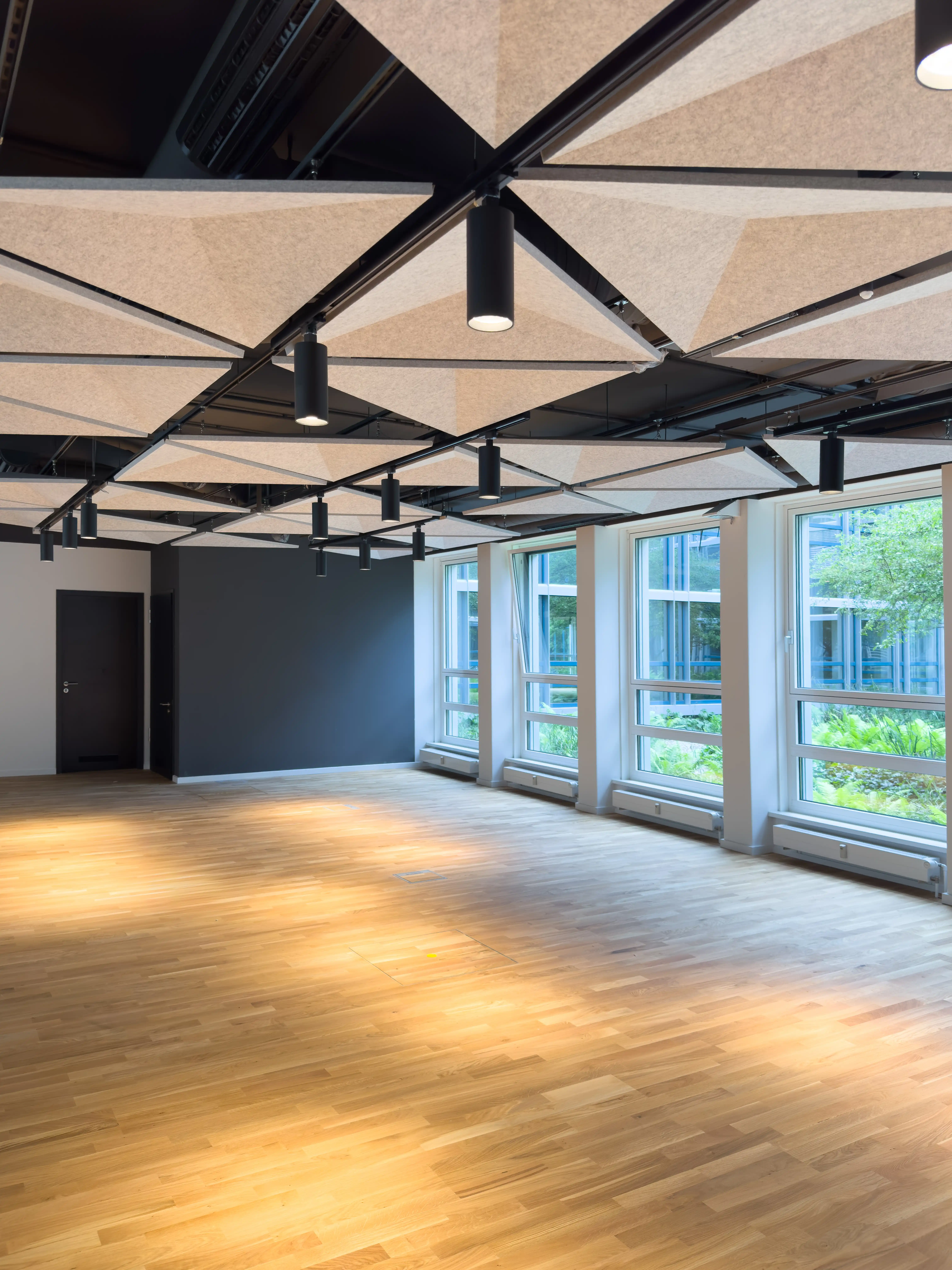 An open industrial-style room with exposed beams and large windows letting in natural light.