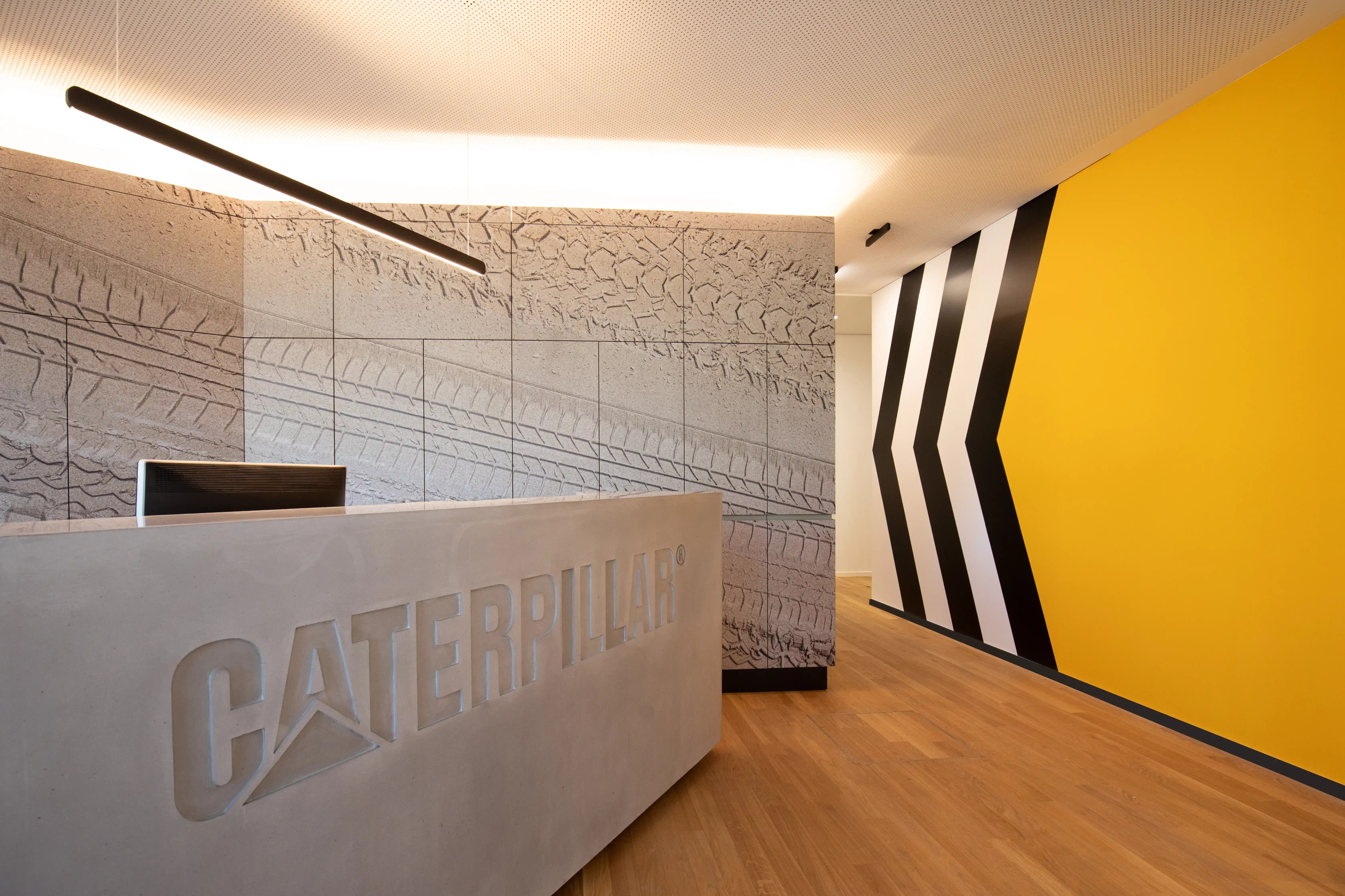 A reception area with a concrete desk, geometric wall patterns, and a bold yellow accent wall.