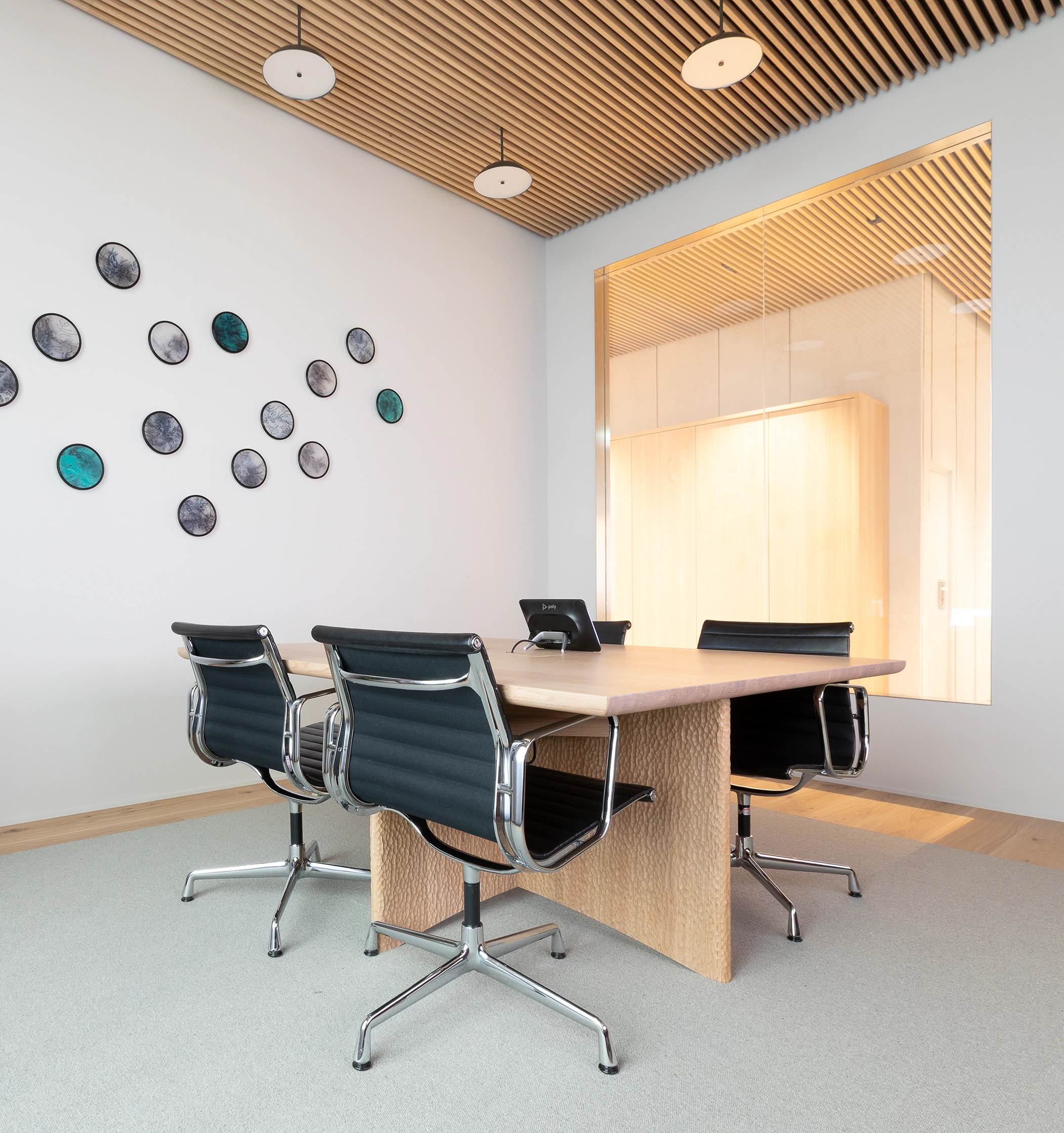 A black-and-white photo of a modern lounge area with round chairs, a low table, and built-in shelving in a minimalist office setting.