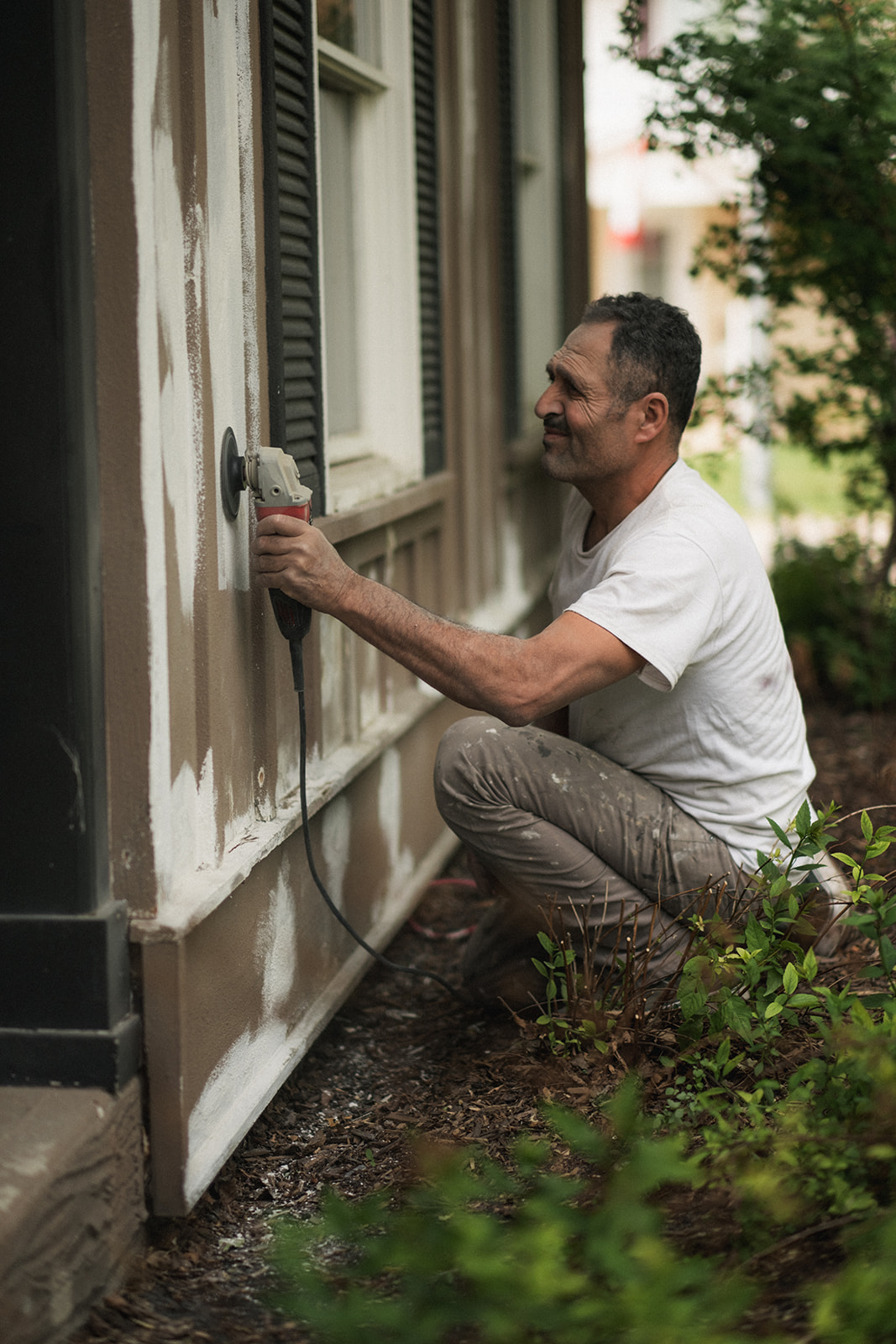 HOA property painting, worker sanding wooden exterior wall