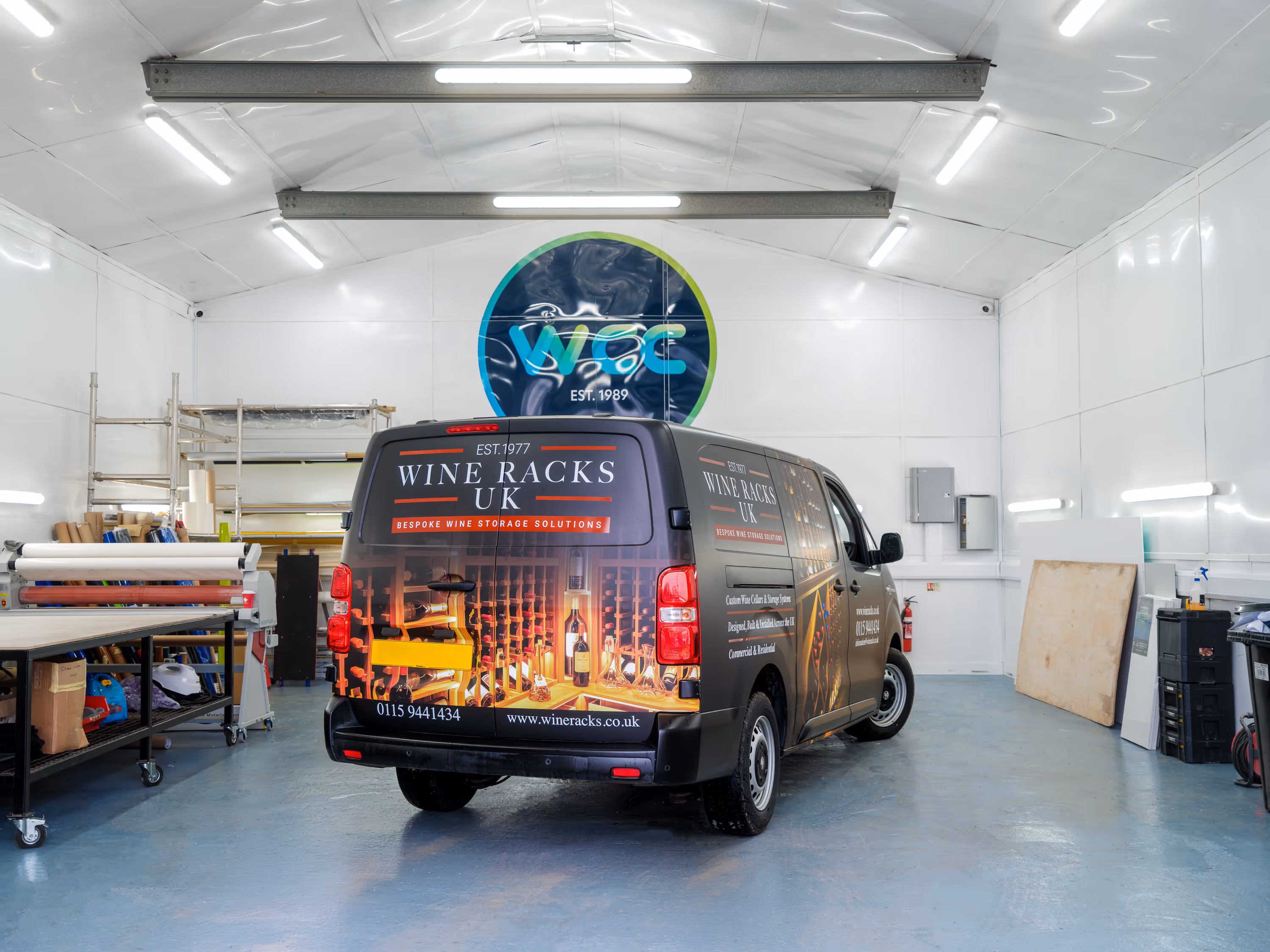 Van inside a bright workshop with Wine Racks UK branding and wine bottle storage graphics on the rear.
