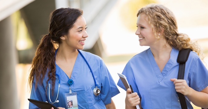 Mature female doctor discussing medical report with nurses in hospital hallway