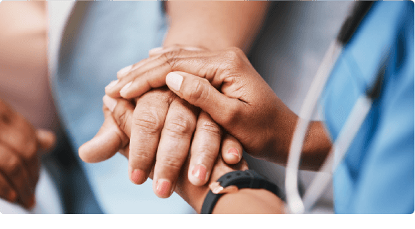 Close-up of one person holding another's hand in a comforting gesture during medical care.