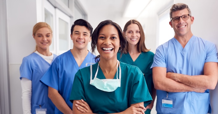 Mature female doctor discussing medical report with nurses in hospital hallway