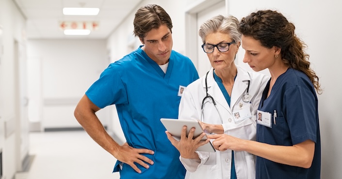 Mature female doctor discussing medical report with nurses in hospital hallway