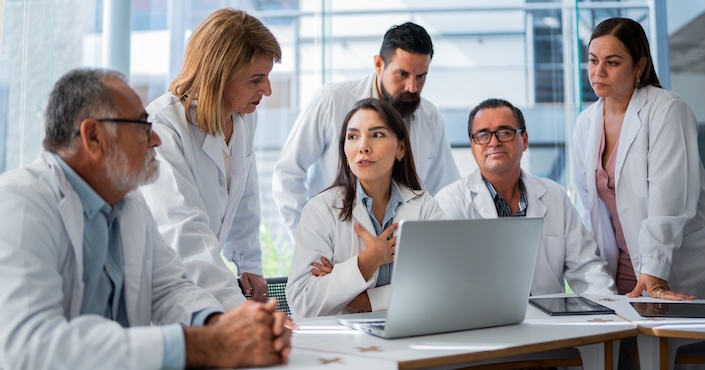 Mature female doctor discussing medical report with nurses in hospital hallway