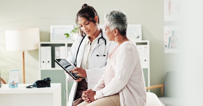 Mature female doctor discussing medical report with nurses in hospital hallway