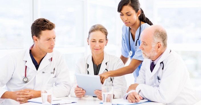 Mature female doctor discussing medical report with nurses in hospital hallway