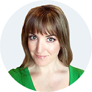 Smiling woman with brown hair and bangs wearing a green shirt against a light background.