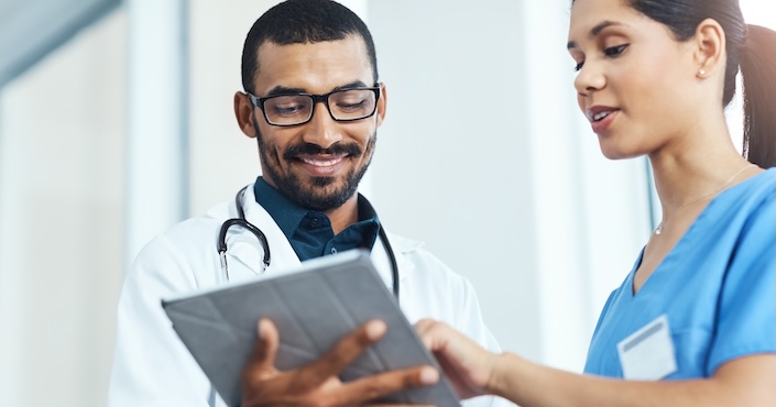 Mature female doctor discussing medical report with nurses in hospital hallway
