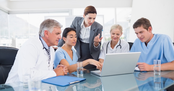 Mature female doctor discussing medical report with nurses in hospital hallway