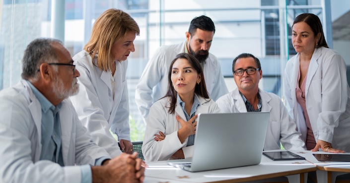 Mature female doctor discussing medical report with nurses in hospital hallway