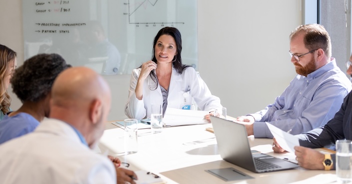 Mature female doctor discussing medical report with nurses in hospital hallway