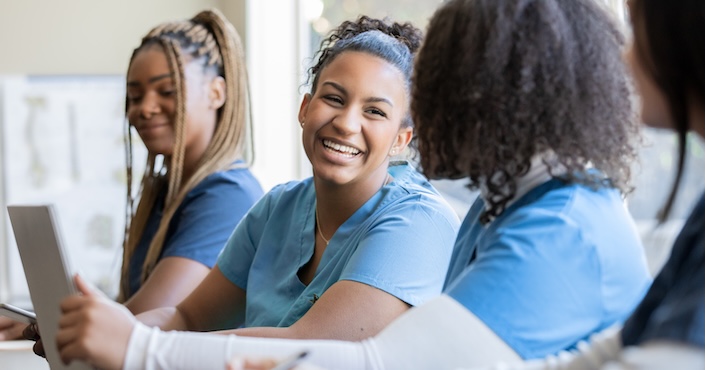 Mature female doctor discussing medical report with nurses in hospital hallway