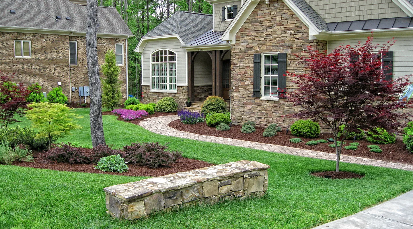  A lush green lawn with decorative landscaping and a sturdy stone bench.