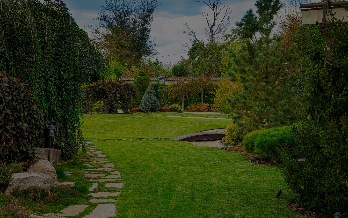  A serene grassy landscape with a stone path bordered by lush trees.