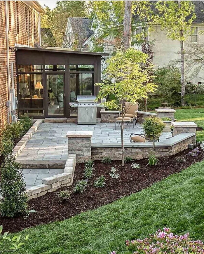 A backyard patio featuring a stone wall and well-maintained landscaping, creating a serene outdoor space.