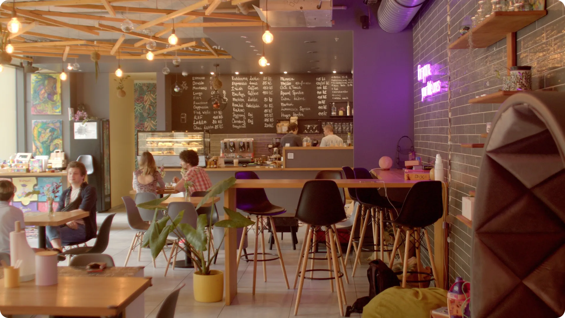 Independent café interior showing diverse customers working, socializing, and gathering in warm community space with natural lighting, plants, and comfortable seating