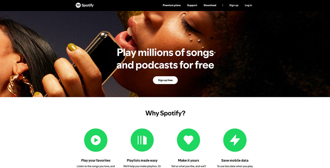 Spotify-Website-Landingpage mit einem Hero-Banner, das Personen mit einem Smartphone zeigt, der Überschrift „Play millions of songs and podcasts for free“ und dem Bereich „Why Spotify?“ mit grünen Symbolen darunter