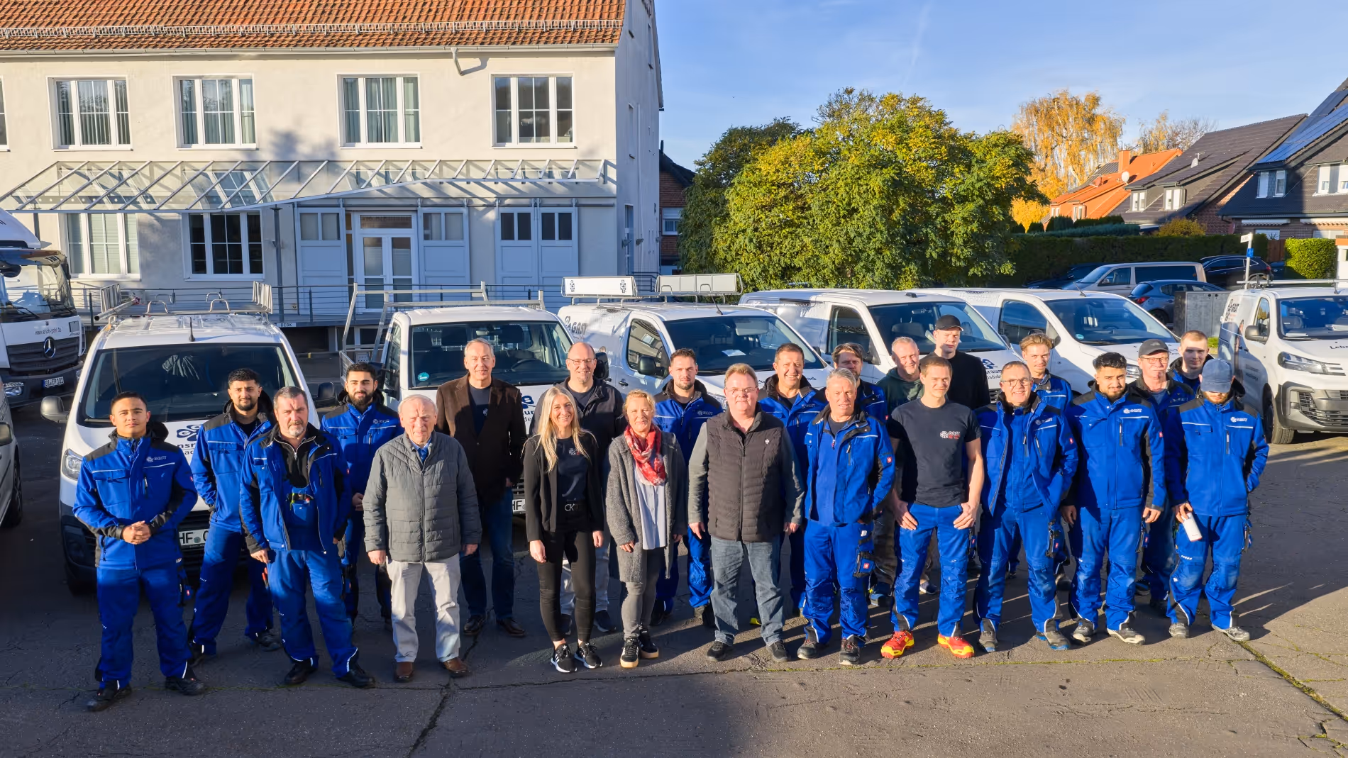 Teamfoto von Gast vor dem Firmengebäude und den Autos