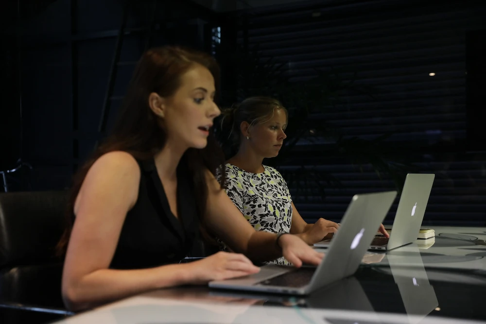 Two women working on a laptop in the office environment
