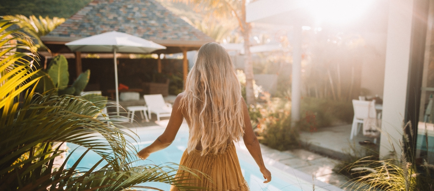 Femme se relaxant au bord d’une piscine turquoise, moment de sérénité et d’élégance tropicale avec MJ Holidays.