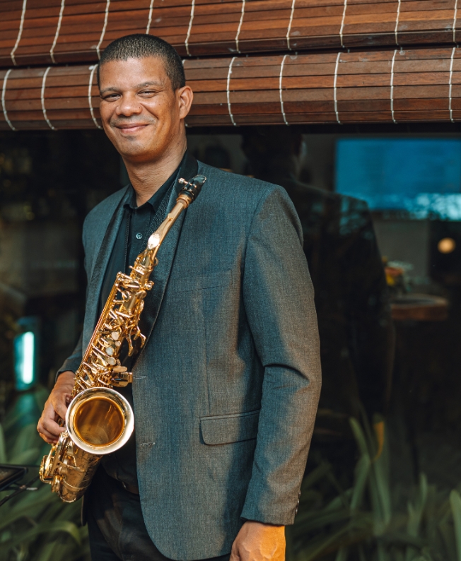 Saxophoniste jouant une mélodie douce au bord de la mer, ambiance élégante et envoûtante signée MJ Holidays.