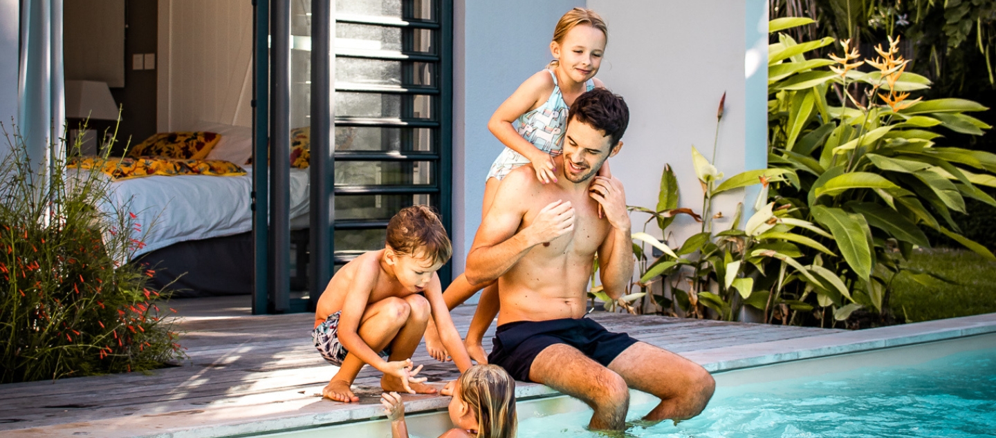 Famille profitant d’un instant de détente au bord d’une piscine turquoise, moment de bonheur et de sérénité avec MJ Holidays.