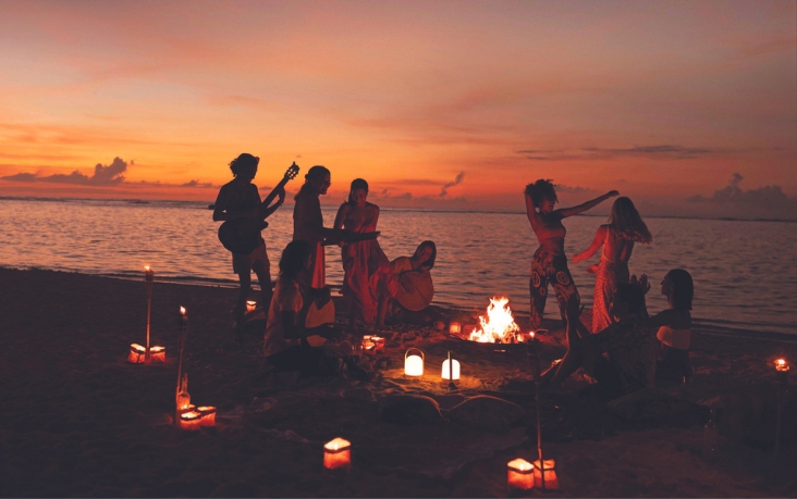 Soirée chaleureuse entre amis sur la plage au coucher du soleil, moment de partage et de douceur tropicale avec MJ Holidays.