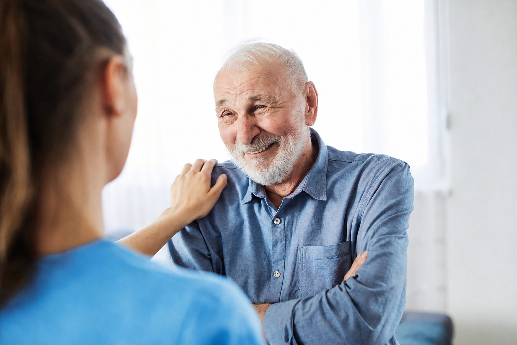 An older man smiling while talking with a nurse at an infusion center