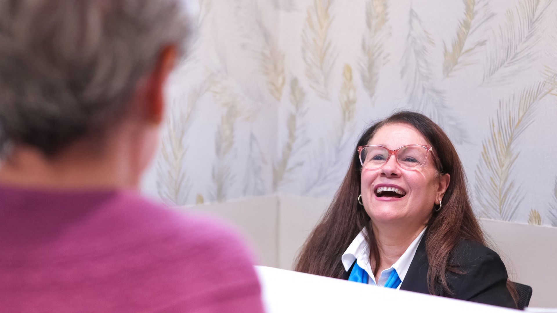A receptionist smiling while helping a patient at an infusion center