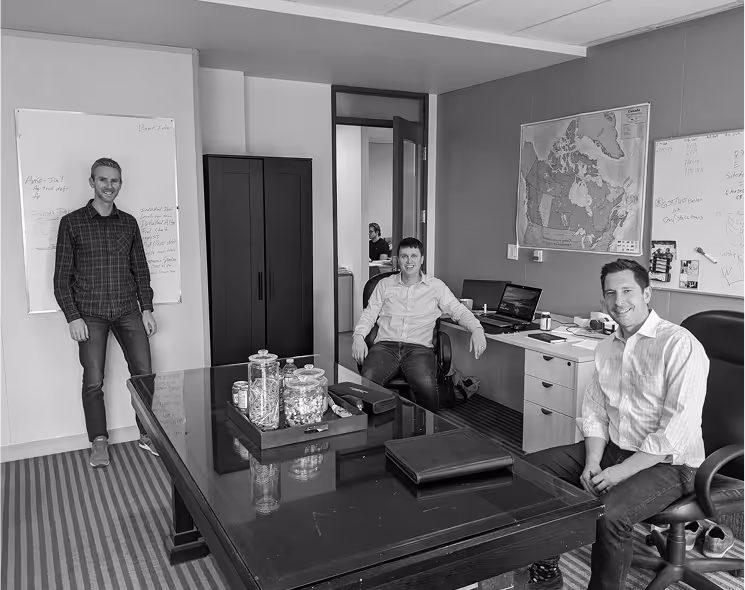 Black and white photo of an office with three Diamond Willow partners.