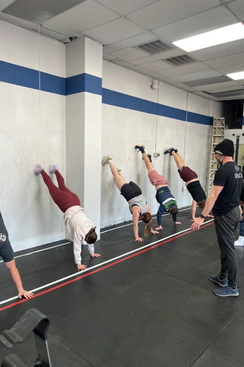 A group of individuals performing push-ups in a gym during a Nutrition Coaching session at CrossFit Empire South, Huntsville, AL.