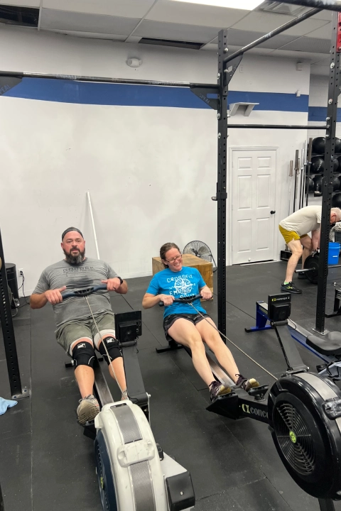 A man and woman rowing together in a gym during a Drop In Fitness Class at CrossFit Empire South, Huntsville, AL.