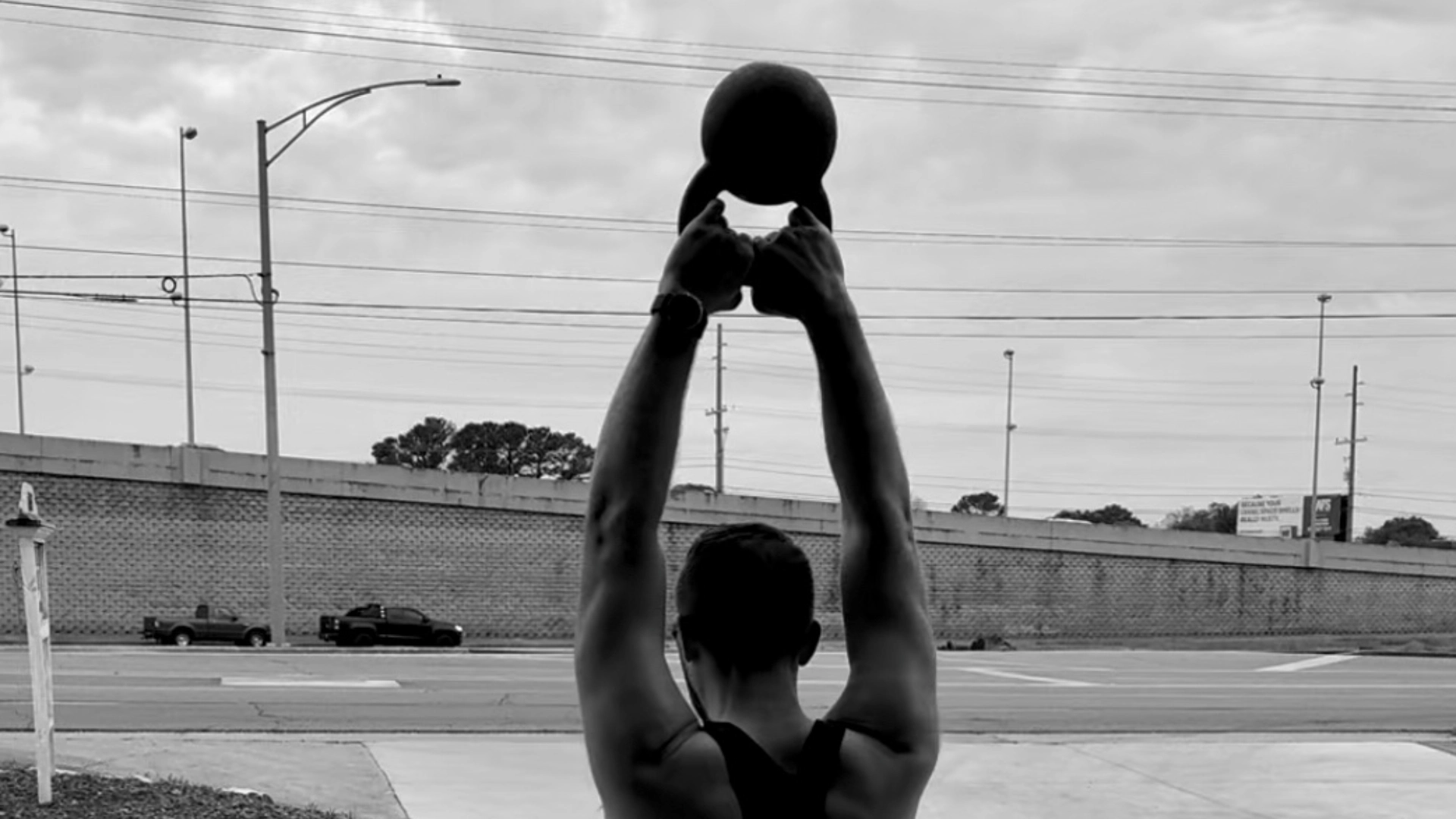 A man holds a kettlebell in an open gym at CrossFit Empire South in Huntsville, AL, showcasing strength training.