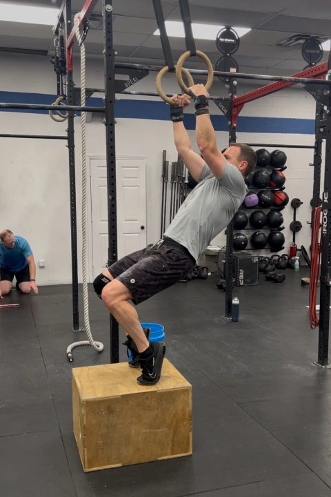 A man performs a pull-up on a gym ring at CrossFit Empire South in Huntsville, AL.