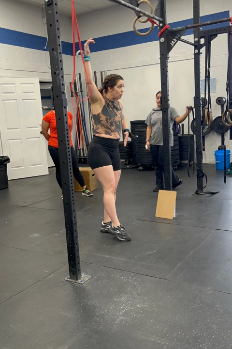A woman performs a pull-up at CrossFit Empire South gym in Huntsville, AL, showcasing strength and determination.