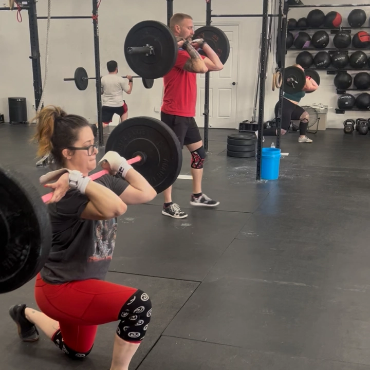 A woman squats with a barbell in a CrossFit gym at CrossFit Empire South in Huntsville, AL.