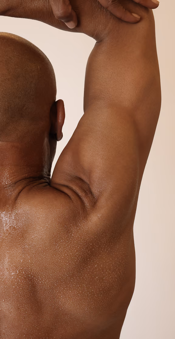 Close-up of a muscular man's back and arm raised, showing skin texture and sweat droplets.