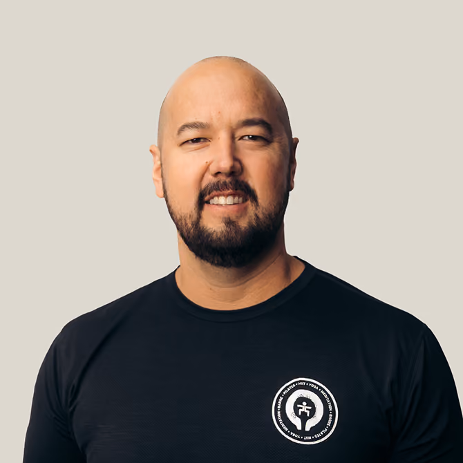 Portrait of a smiling bald man with a beard wearing a black t-shirt with a circular logo on the chest.