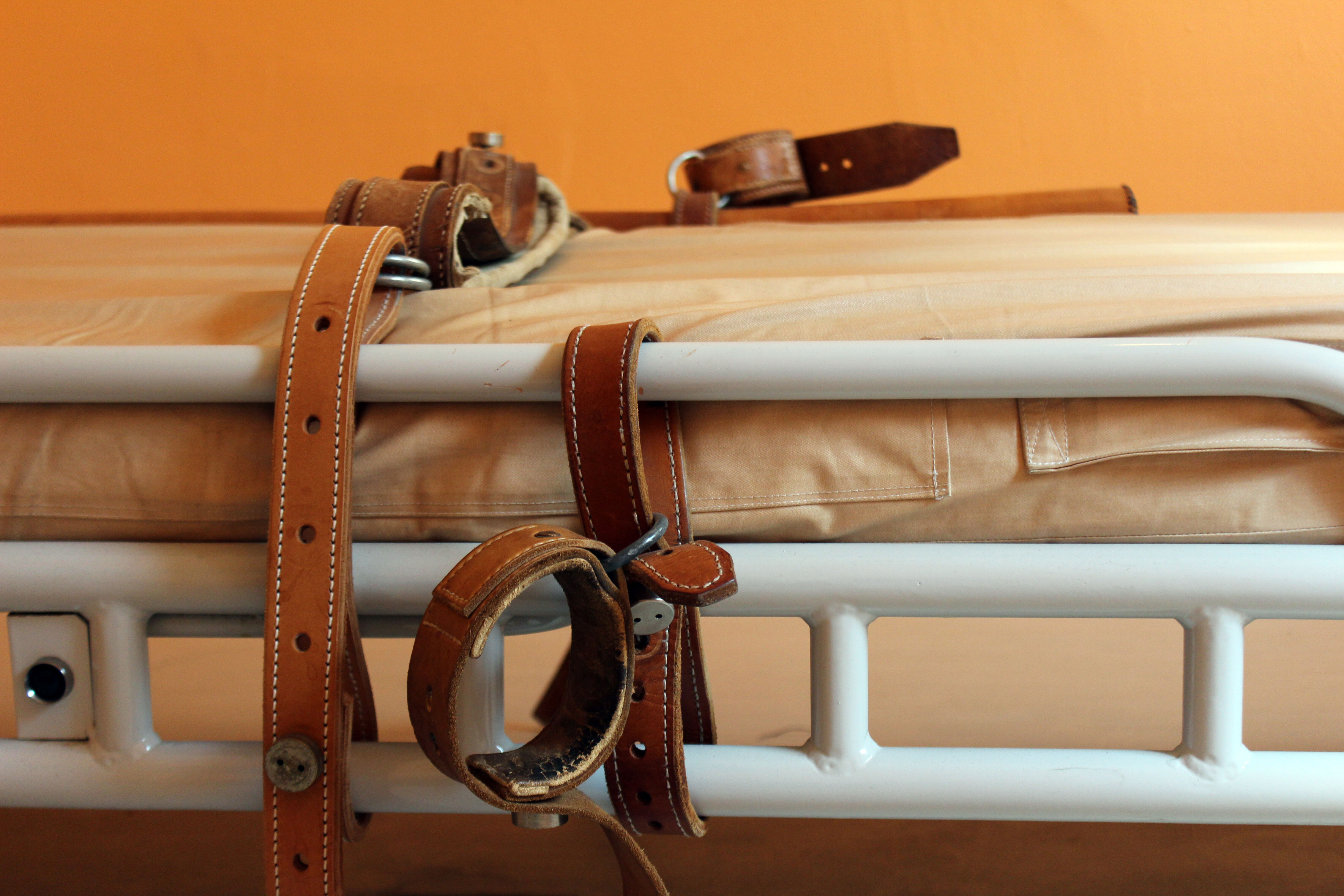 Gros plan sur un bracelet en cuir et une ceinture fixés à un lit d’hôpital psychiatrique, utilisés pour les mesures coercitives.