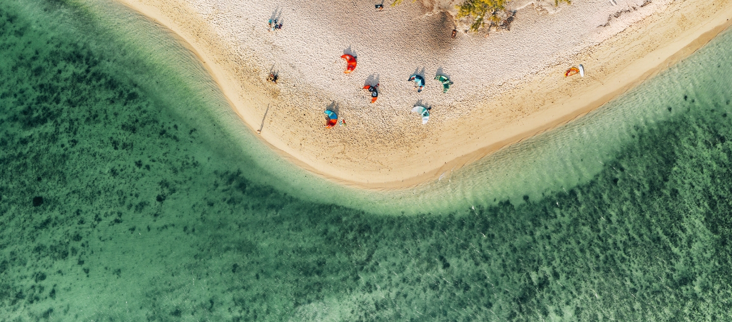 Vue aérienne d’une plage de sable blanc et d’une eau turquoise à l’île Maurice, illustrant la beauté naturelle des destinations MJ Holidays.