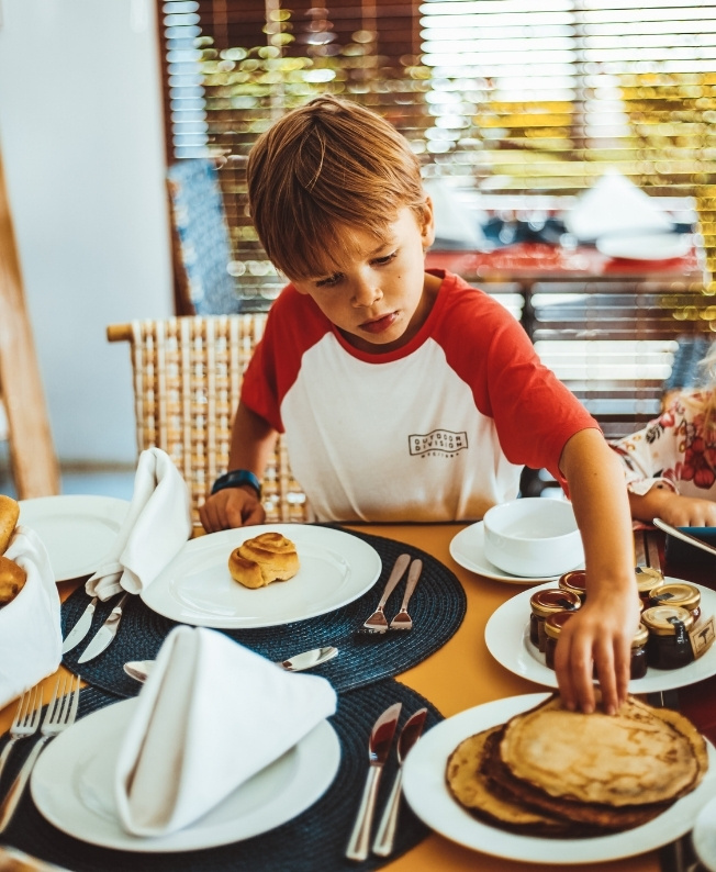 Un enfant se servant au buffet du brunch Let’s Eat & Play Together à l’île Maurice, profitant d’un moment joyeux et familial organisé par MJ Holidays.