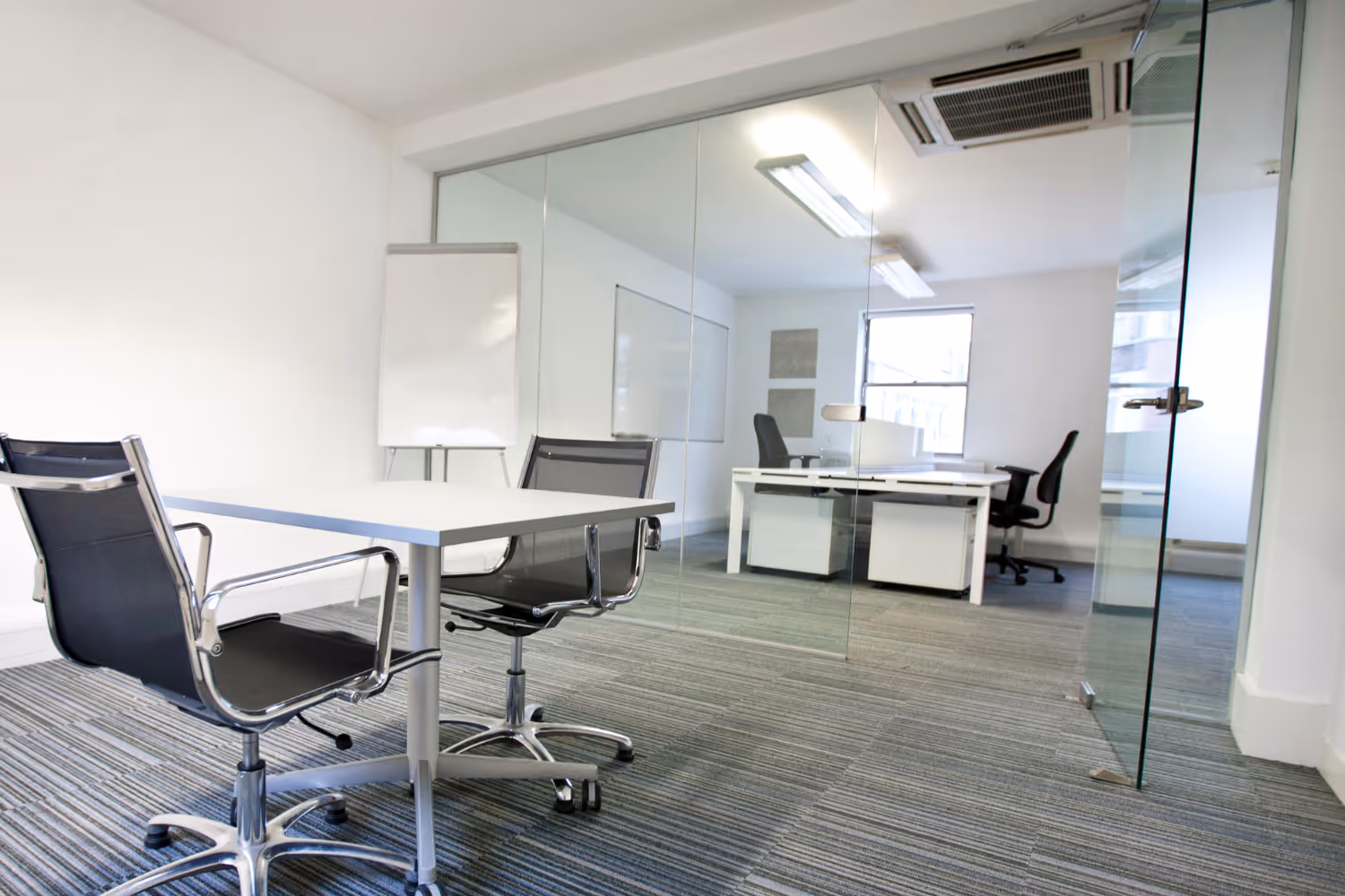 A white office room with a table and chairs.
